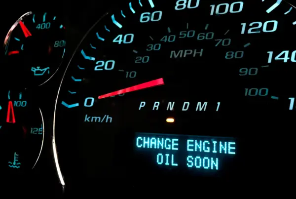 A car's illuminated dashboard display showing the message "Change engine oil soon" beside the speedometer.
