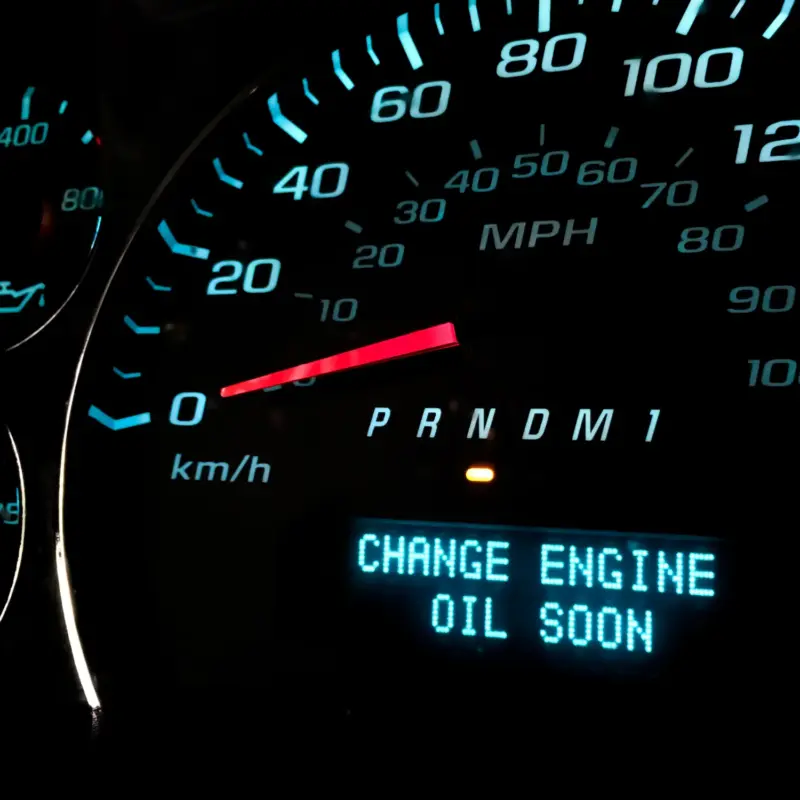 A car's illuminated dashboard display showing the message "Change engine oil soon" beside the speedometer.