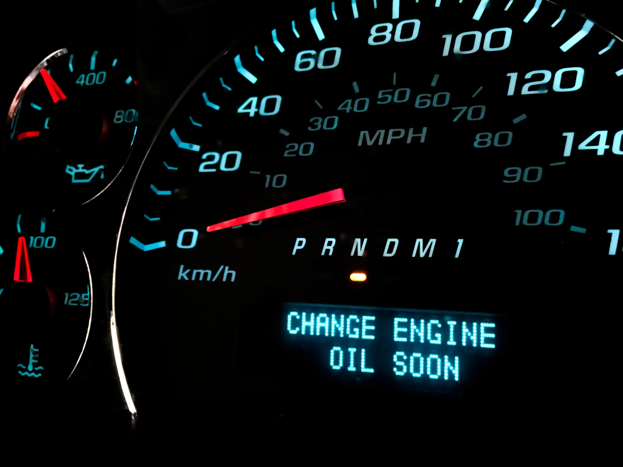 A car's illuminated dashboard display showing the message "Change engine oil soon" beside the speedometer.